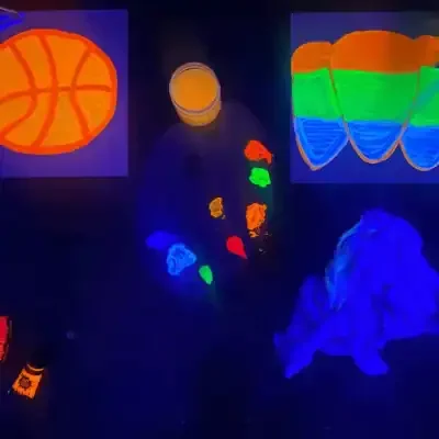 Glow-in-the-dark paintings of a basketball, a rainbow, and a glass of juice.